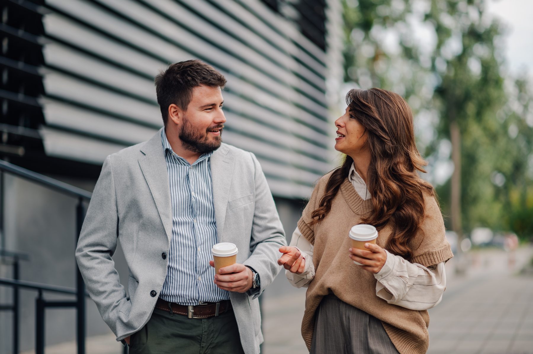 Two people in conversation, walking with coffee