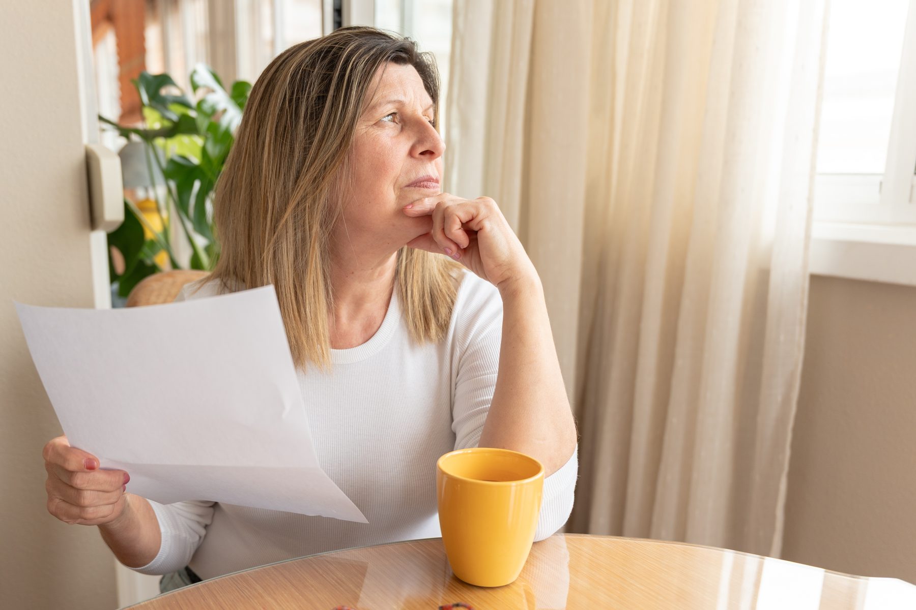A woman at home reviewing papers, thinking about her giving